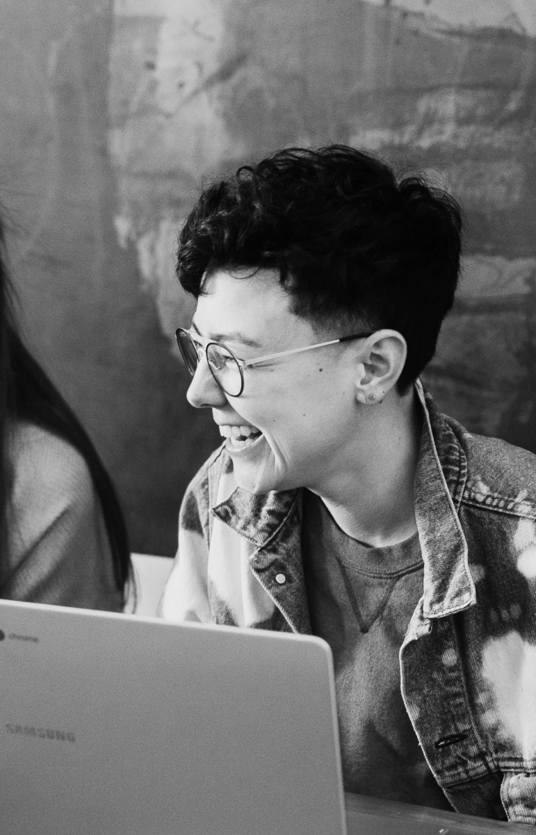 Black and white photo of a person laughing while sitting in front of their computer.